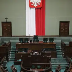 Pusta sala sejmowa z godłem Polski i flagą. Krzesła czekają na posłów, by podjąć decyzje, które kształtują większość konstytucyjną.