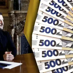Wołodymyr Zełenski siedzi przy stole, obok stos ukraińskich banknotów 500 hrywien.
