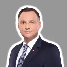 Prezydent Andrzej Duda w garniturze, z biało-czerwoną flagą na klapie. Jego uśmiech sugeruje ułaskawienie prezydenta Nawrockiego.