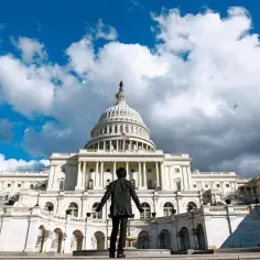 Osoba stoi przed majestatycznym budynkiem Kongresu USA, patrząc na jego kopułę.